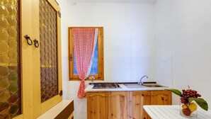 A kitchen with wooden cabinets, a white countertop, a sink, and a window with a checkered curtain. - Holiday Apartment "La Vista di Mondo" on the Beach with Sea View, Terrace & Garden (Torre dei Corsari Arbus)
