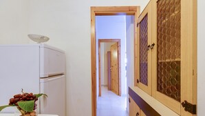 A hallway with a refrigerator, a cabinet with a glass door, and a table with a vase of fruit. - Holiday Apartment "La Vista di Mondo" on the Beach with Sea View, Terrace & Garden (Torre dei Corsari Arbus)