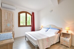 A bedroom with a bed, bedside tables, a window with curtains, and a wooden wardrobe.
