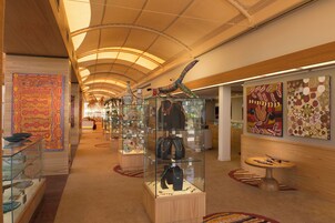 A corridor with glass display cases containing jewelry, a wooden bench, and a carpeted floor.