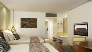 Habitación de hotel moderna con cama, zona de estar, televisor y obras de arte en las paredes.