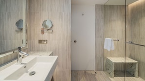 Un baño moderno con un espejo grande, un lavamanos y una zona de ducha.