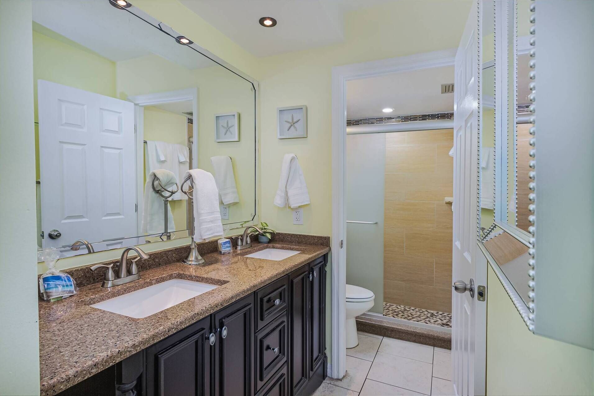 A bathroom with two sinks, a large mirror, and a shower area.
