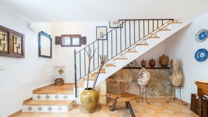 A staircase with a metal railing, a vase, and pottery on the landing.