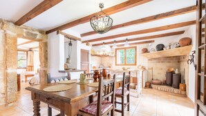 A rustic kitchen with wooden beams, a stone wall, and a tiled floor.