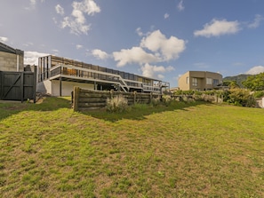 Un edificio moderno con un espacio exterior techado, una valla de madera y un campo cubierto de césped.