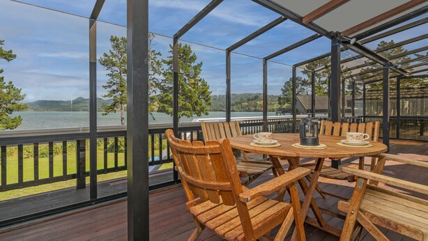 A wooden deck with a table and chairs overlooking a lake. - Sheppard's Rest - Pauanui Holiday Home (Pauanui)