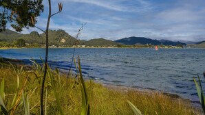 A lake with a sailboat, surrounded by greenery and hills. - Sheppard's Rest - Pauanui Holiday Home (Pauanui)