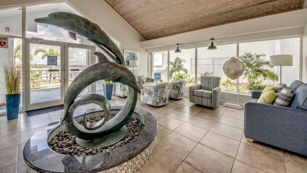 A lobby with a modern sculpture, comfortable seating, and large windows. - Ocean Harbor #1201B Beautiful Bayfront Condo (Fort Myers Beach)