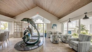 A lobby with a dolphin sculpture, modern furniture, and large windows. - Ocean Harbor #1201B Beautiful Bayfront Condo (Fort Myers Beach)