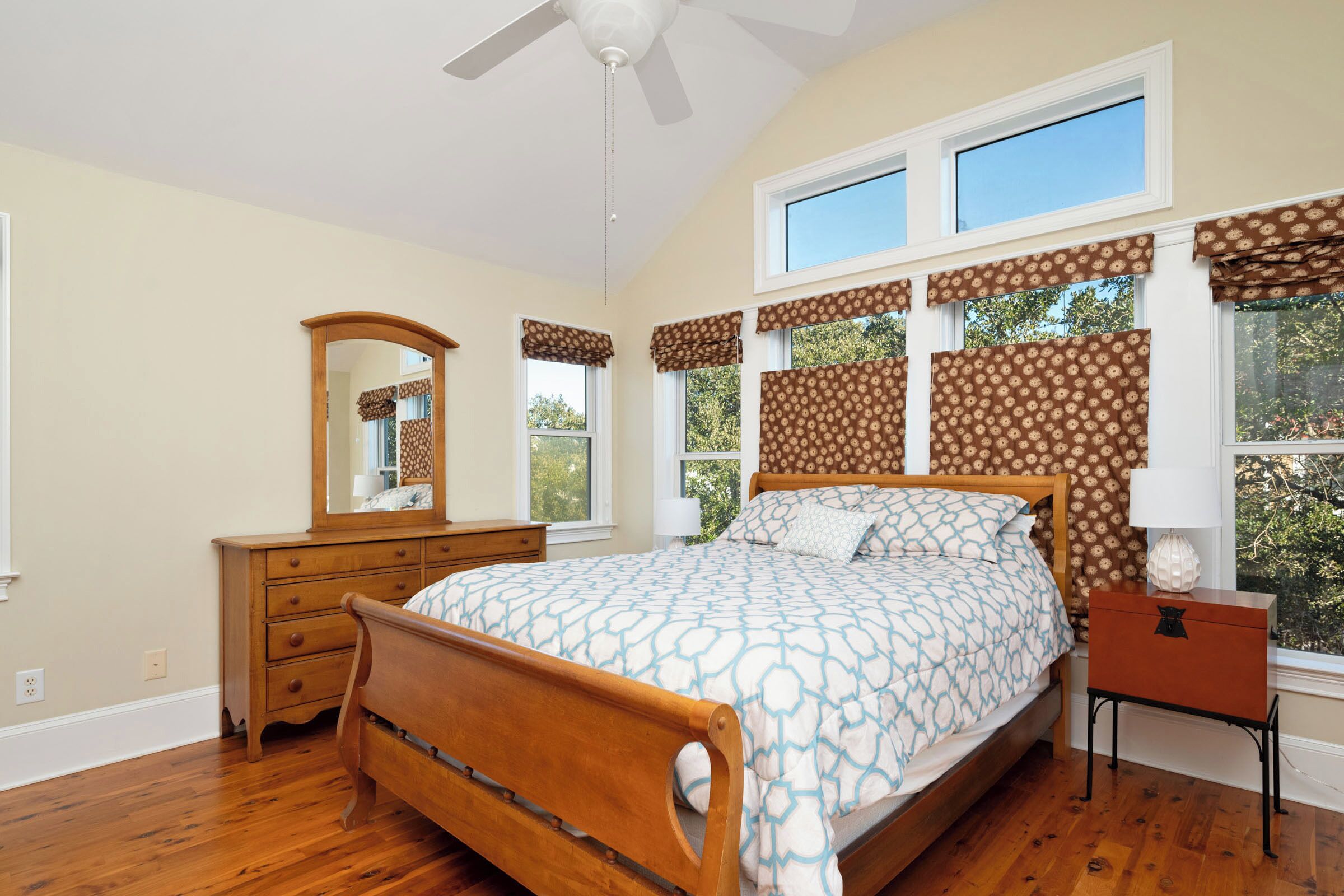 Un dormitorio con una cama de madera, un aparador, un espejo y una mesita de noche.