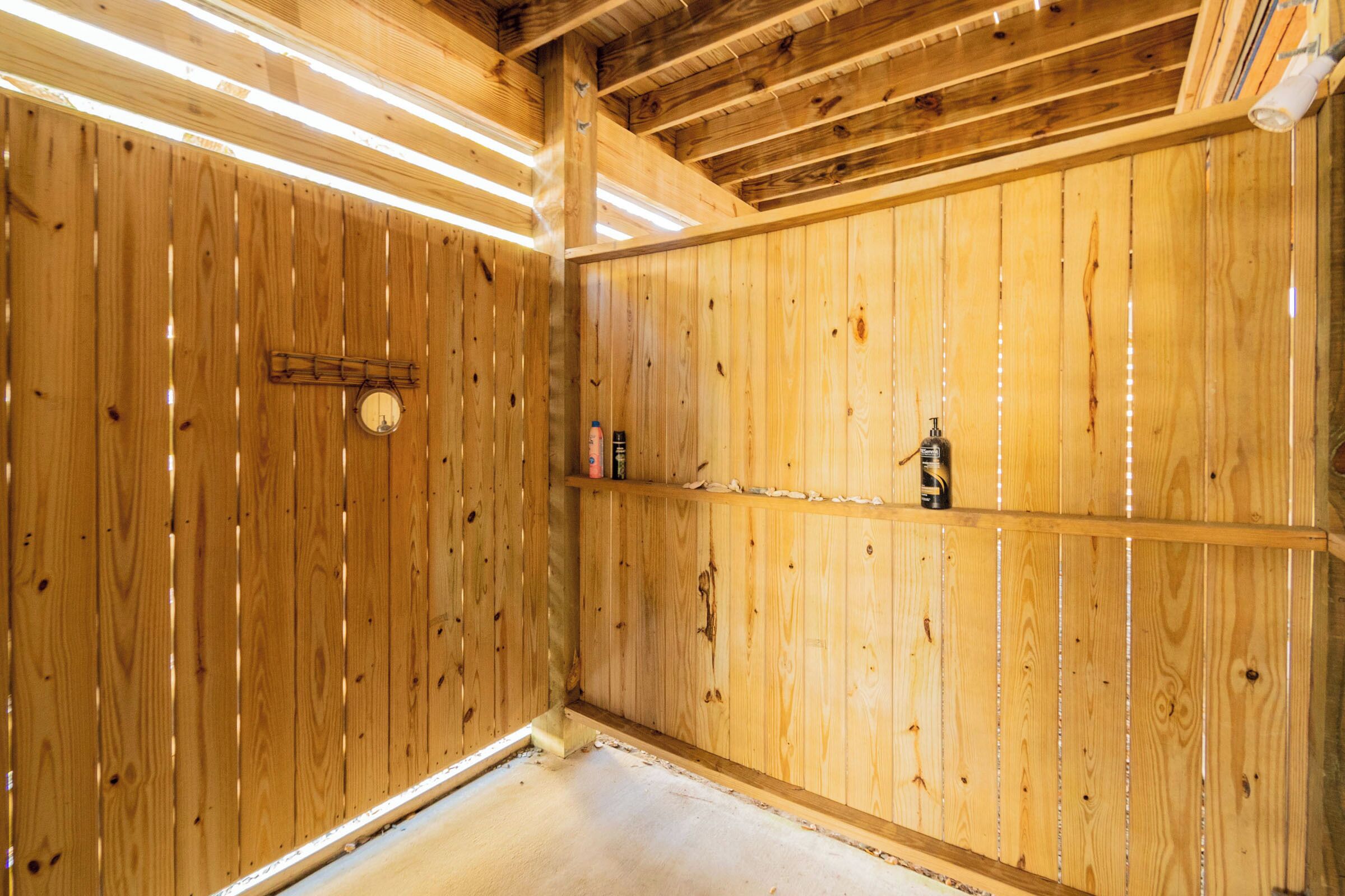 A wooden interior with a wooden ceiling, a shelf with a bottle, and a small circular object on the wall.