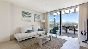 A modern living room with a sofa, coffee table, and a view of a dining area with a table and chairs.