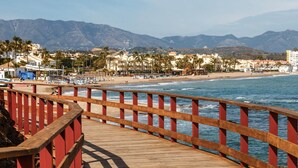 A wooden boardwalk leading to a beach with mountains in the background.