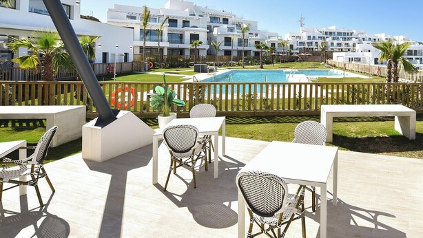 A communal terrace with a pool, garden, and seating area.