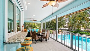 A covered outdoor area with a pool, seating, and a ceiling fan.