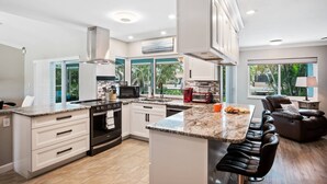 A modern kitchen with a central island, built-in oven, and a dining area with a bar stool.
