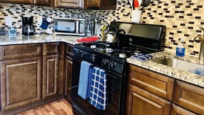 A kitchen with wooden cabinets, a microwave, a stove, and a tiled backsplash.