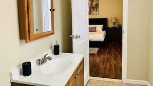 A bathroom with a wooden-framed mirror, a white sink, and a black soap dispenser.
