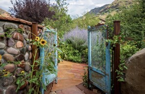 A stone wall with a metal gate leading to a stone pathway.