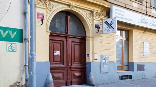 A building with a large wooden double door, a sign for a cosmetology studio, and a green bicycle parking sign. - Great room near city centre - private bathroom (Prague 2)