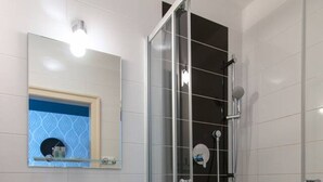 A bathroom with a glass-enclosed shower, a white sink, and a mirror with a blue patterned wall. - Great room near city centre - private bathroom (Prague 2)