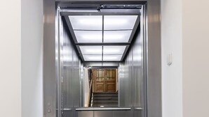 A modern elevator with a metallic interior and a glass panel at the top. - Great room near city centre - private bathroom (Prague 2)