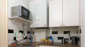 A compact kitchen with white cabinets, a microwave, a kettle, and a coffee maker. - Wonderful room downtown with ensuite bathroom (Prague 2)
