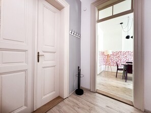 Un pasillo con una puerta blanca, un perchero y vistas a un comedor con una mesa y sillas.