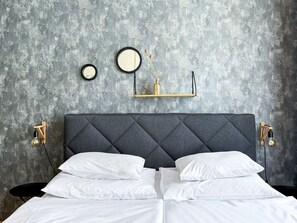 A bed with a tufted headboard, white bedding, and two wall-mounted light fixtures.