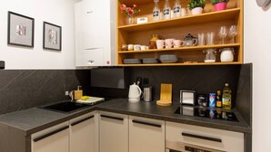A modern kitchen with a black countertop, wooden shelves, and a built-in oven.