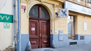 A building facade with a large double wooden door, a sign for a permanent makeup studio, and a green bicycle parking sign.