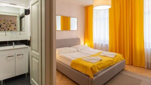 A hotel room with a bed, a bathroom with a mirror, and a window with curtains.
