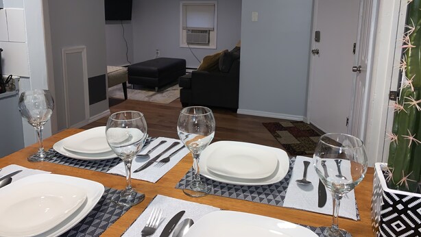 Een eethoek met een tafel gedekt voor vier personen, inclusief borden, bestek en wijnglazen.