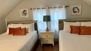 Een hotelkamer met twee bedden, een nachtkastje met een lamp en een raam met gordijnen.