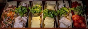 A buffet with various food items including sliced meats, cheeses, and fresh vegetables. - Hotelli Mesikämmen Oy (Ahtari)