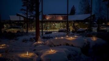 A modern building with a glass facade, surrounded by snow-covered ground and trees.