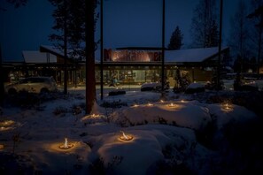 A modern building with a glass facade, surrounded by snow-covered ground and trees. - Hotelli Mesikämmen Oy (Ahtari)