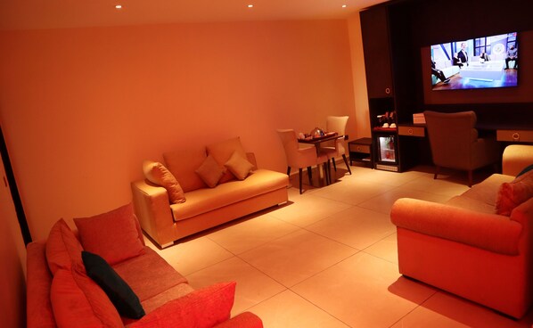 A modern living room with a sofa, chairs, a coffee table, and a television.