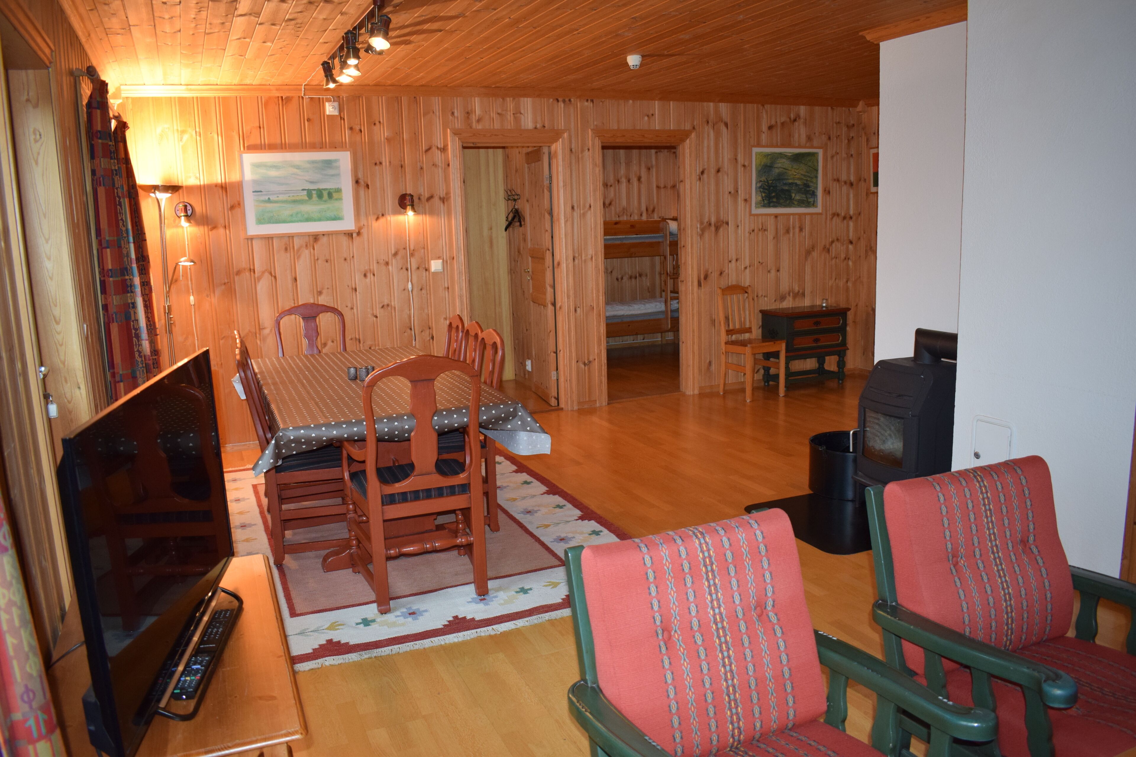 Un interior de madera con una mesa de comedor, sillas, un sofá, un televisor y una chimenea.