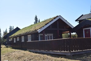 A wooden cabin with a grass roof, a wooden deck, and a clear sky. - Skeikampen Booking (Gausdal)