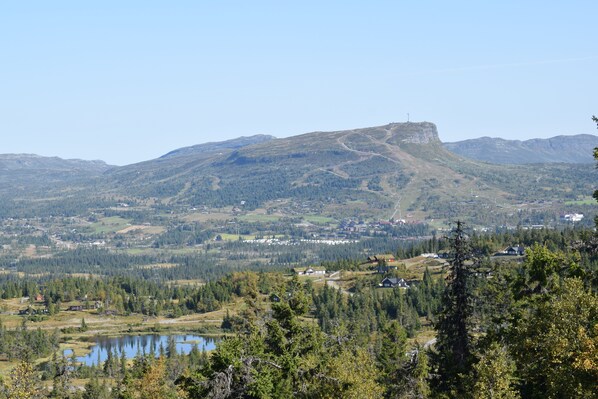 A mountainous landscape with a lake, forested areas, and a small settlement with buildings. - Skeikampen Booking (Gausdal)