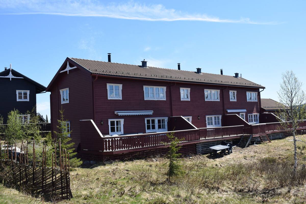 A two-story house with a red exterior, white trim, and multiple windows.