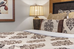 A neatly made bed with patterned bedding, a bedside lamp, and decorative pillows.