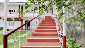A staircase with red steps and white railings leading to a building with a reception sign. - Treebo Atithi Bhavan, 1 Km From Ooty Lake (Ootacamund)