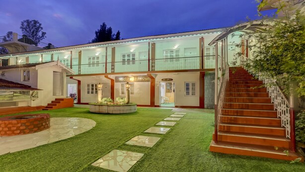 A hotel with a courtyard featuring a fountain, a reception area, and a staircase leading to the upper floors. - Treebo Atithi Bhavan, 1 Km From Ooty Lake (Ootacamund)
