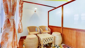 A corner room with two wicker chairs, a small table, and a round stool. - Treebo Atithi Bhavan, 1 Km From Ooty Lake (Ootacamund)