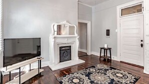 Una sala de estar con chimenea, televisor y alfombra estampada.