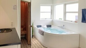 A bathroom with a bathtub, a sink, a window, and a door leading to a wooden closet.