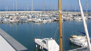 Un port de plaisance où de nombreux bateaux sont amarrés, l’eau est calme et le ciel est dégagé.